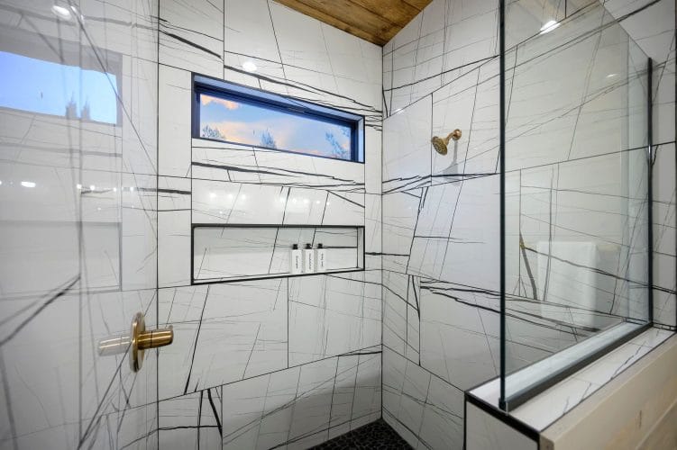 Shower with veined white tile and a window above