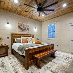 King bed with a reclaimed-wood frame and bench, wood ceiling and fan on the main floor