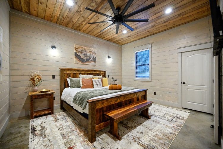 King bed with a reclaimed-wood frame and bench, wood ceiling and fan on the main floor
