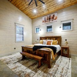King bed with a reclaimed-wood frame, bench and a horse painting over the bed