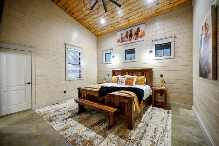 King bed with a reclaimed-wood frame, bench and a horse painting over the bed