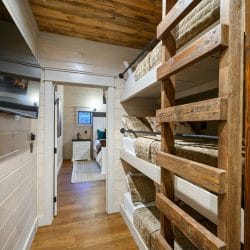 Hallway with bunk beds and a TV, leading toward another bedroom
