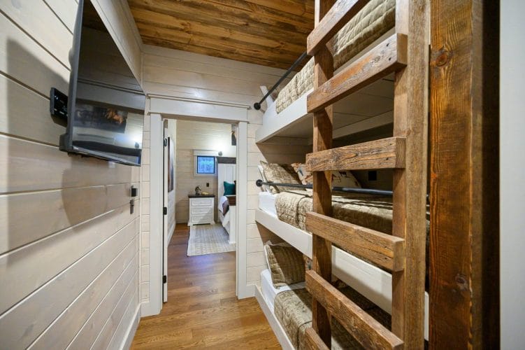 Hallway with bunk beds and a TV, leading toward another bedroom