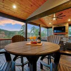 Round table with tall chairs on the covered deck, hills in the background