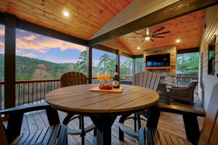 Round table with tall chairs on the covered deck, hills in the background