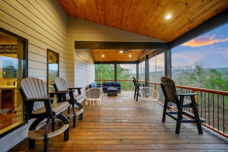 Long covered deck with tall chairs and a swing at the far end