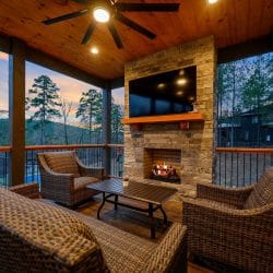 Wicker seating facing a stone fireplace and TV on the covered patio