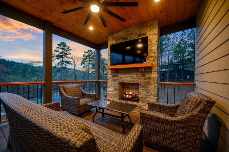 Wicker seating facing a stone fireplace and TV on the covered patio