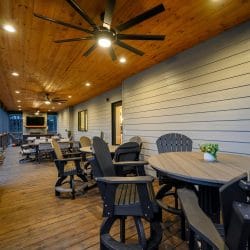 Covered deck with high-top tables and chairs and a ceiling fan