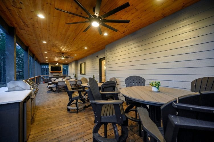 Covered deck with high-top tables and chairs and a ceiling fan