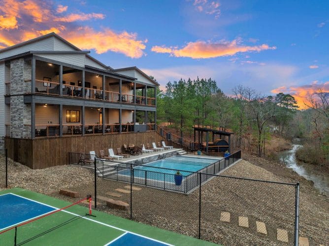 Stacked decks of the lodge above the pool, with the sports court and creek below
