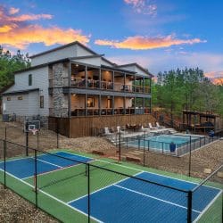 Lodge, pool and sports court with the creek beyond, at dusk