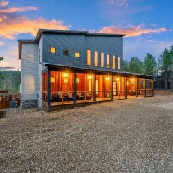 Back of the lodge with lit windows seen across the gravel lot at dusk