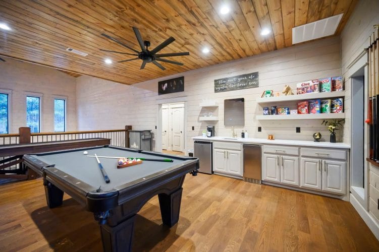 Pool table next to a bar counter with a shelf of snacks