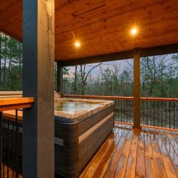 Hot tub on the covered deck, wet wood and railing at dusk