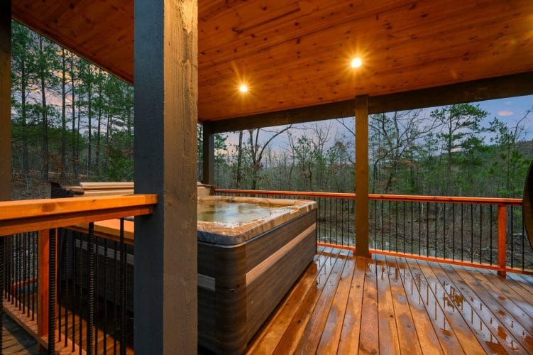Hot tub on the covered deck, wet wood and railing at dusk