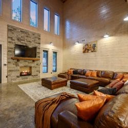Leather sectional and ottomans in front of a stone fireplace and TV