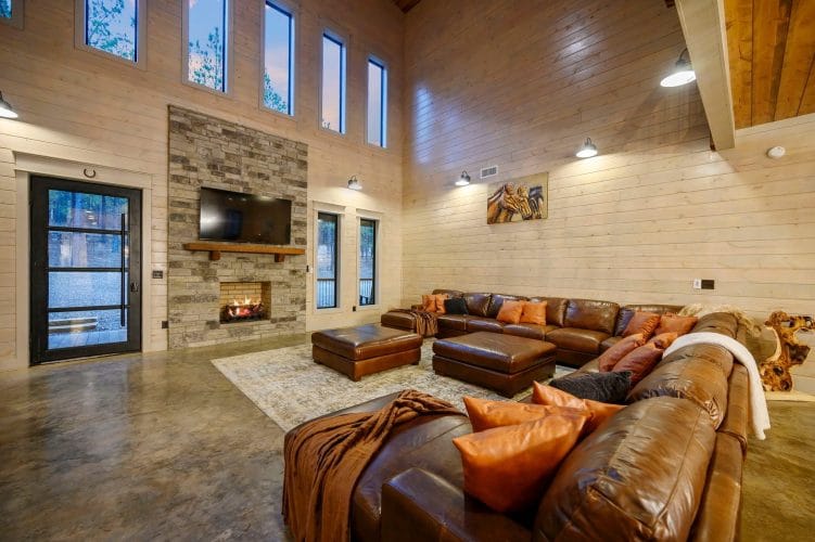 Leather sectional and ottomans in front of a stone fireplace and TV