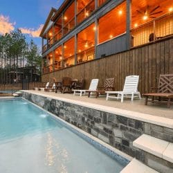 Pool with a stone wall and loungers, the lodge deck above