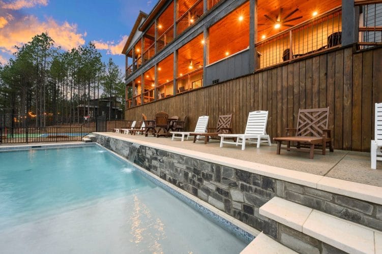 Pool with a stone wall and loungers, the lodge deck above