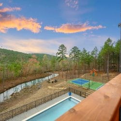 Creek, fire pit area and sports court seen from above, with hills at dusk