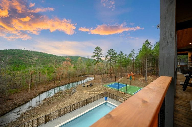 Creek, fire pit area and sports court seen from above, with hills at dusk