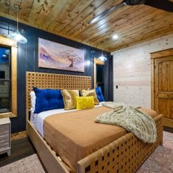 King bed with tan cover and a woven wood headboard under a ceiling fan