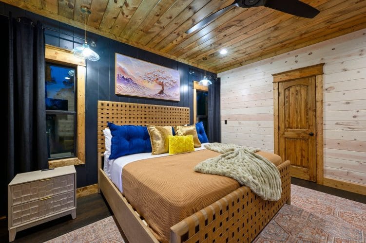 King bed with tan cover and a woven wood headboard under a ceiling fan