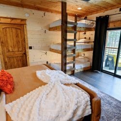 King bed with a stack of bunk beds and a sliding door to the balcony behind