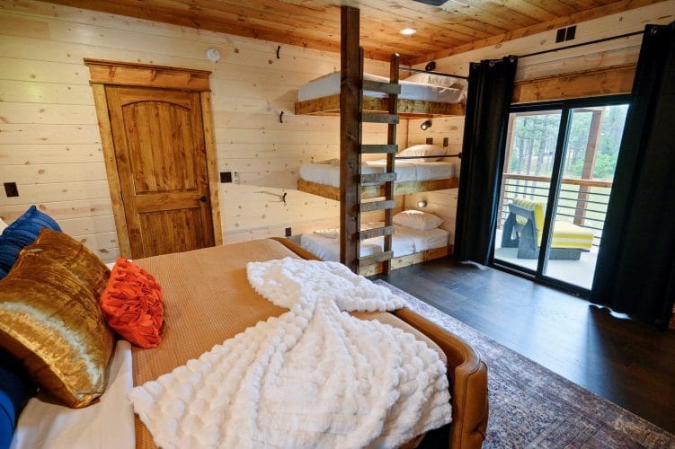 King bed with a stack of bunk beds and a sliding door to the balcony behind