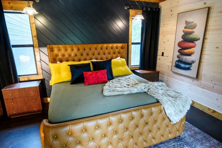 King bed with a tufted leather headboard, green cover and yellow pillows