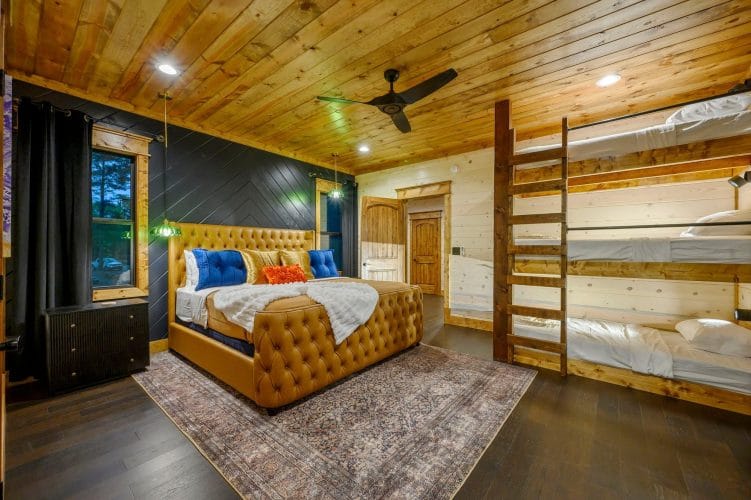 Tufted king bed with a triple-stacked bunk against the right wall