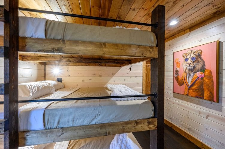 Stacked bunk beds with gray bedding and an animal portrait on the wall