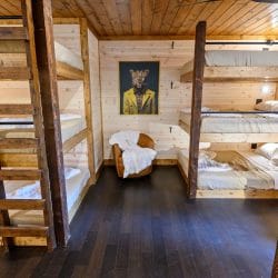 Triple-stacked bunk beds on both sides of a room with a chair at the end