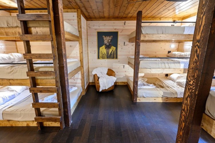 Triple-stacked bunk beds on both sides of a room with a chair at the end