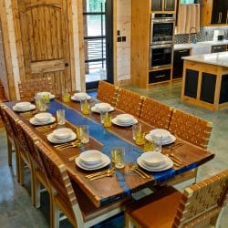 Long dining table set with plates, kitchen island beyond
