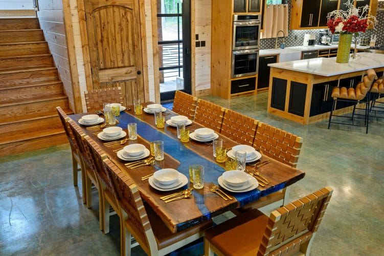 Long dining table set with plates, kitchen island beyond