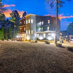 House at night with lit windows and gravel yard