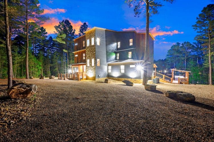 House at night with lit windows and gravel yard