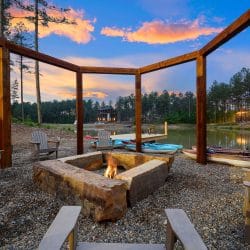 Fire pit under a timber frame beside the pond at sunset