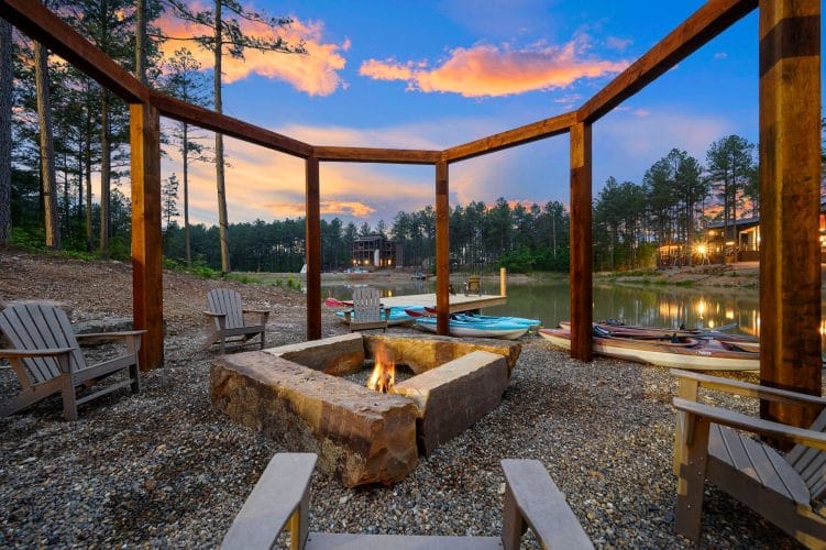 Fire pit under a timber frame beside the pond at sunset