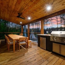 Covered deck with a built-in grill, outdoor fridge and a long dining table