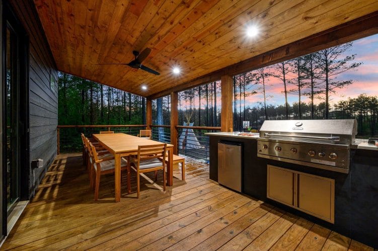 Covered deck with a built-in grill, outdoor fridge and a long dining table