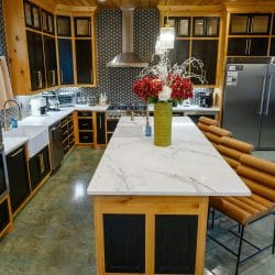 Kitchen island and double ovens with a refrigerator at right