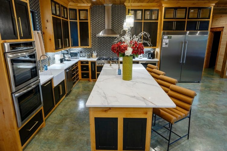 Kitchen island and double ovens with a refrigerator at right