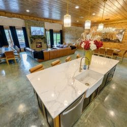 Kitchen island with the living room and stone fireplace under high windows