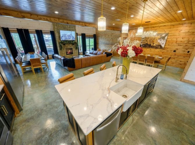 Kitchen island with the living room and stone fireplace under high windows
