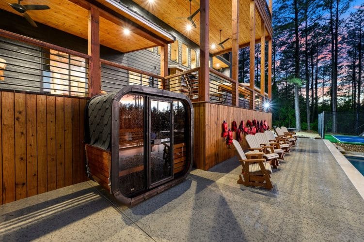 Outdoor wood sauna cabin beside rocking chairs on the pool deck