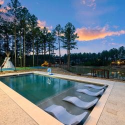 Pool with in-water loungers, a teepee and the pond behind it