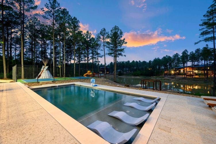 Pool with in-water loungers, a teepee and the pond behind it